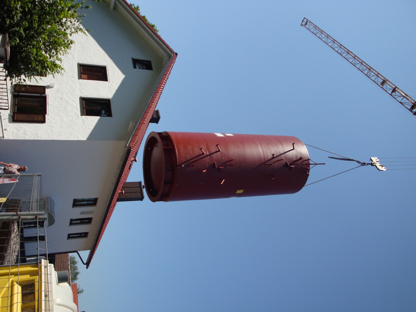 Pufferspeicher mit 15.000 Litern wird per Kran über ein Wohnhaus gehoben